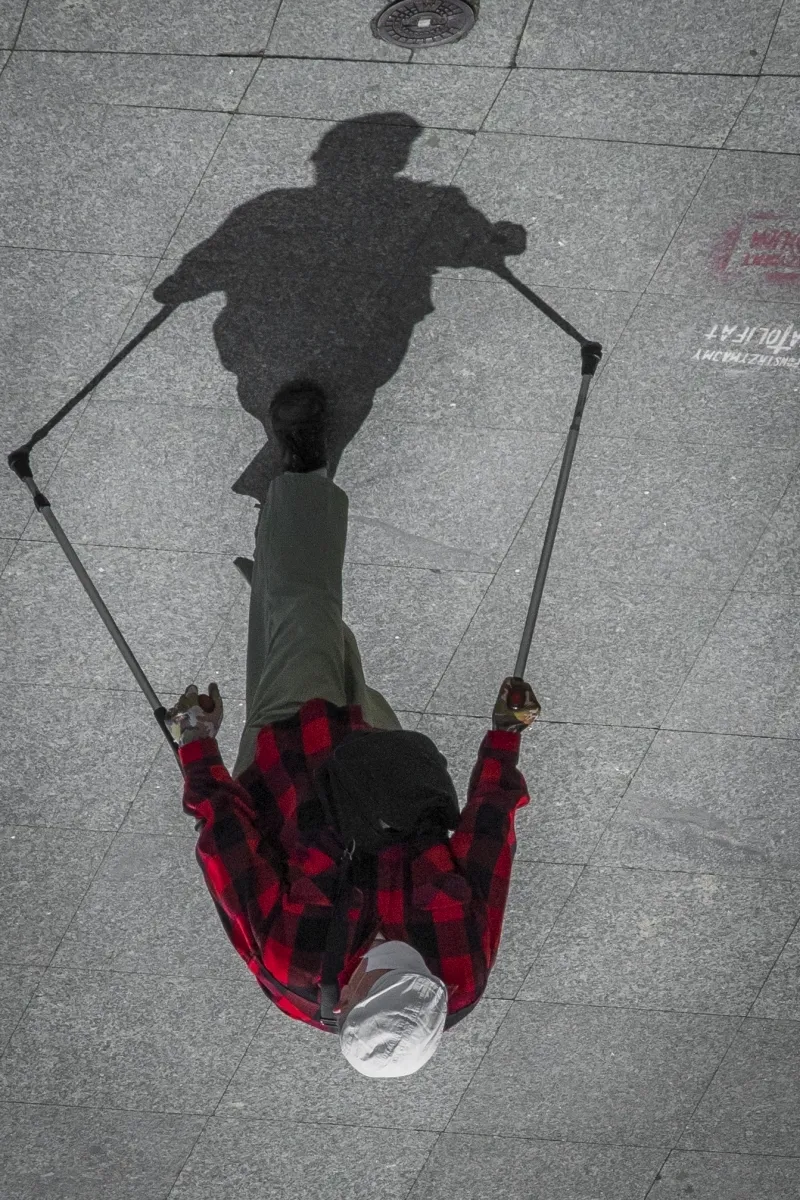 Shadow of a person using walking poles on the pavement